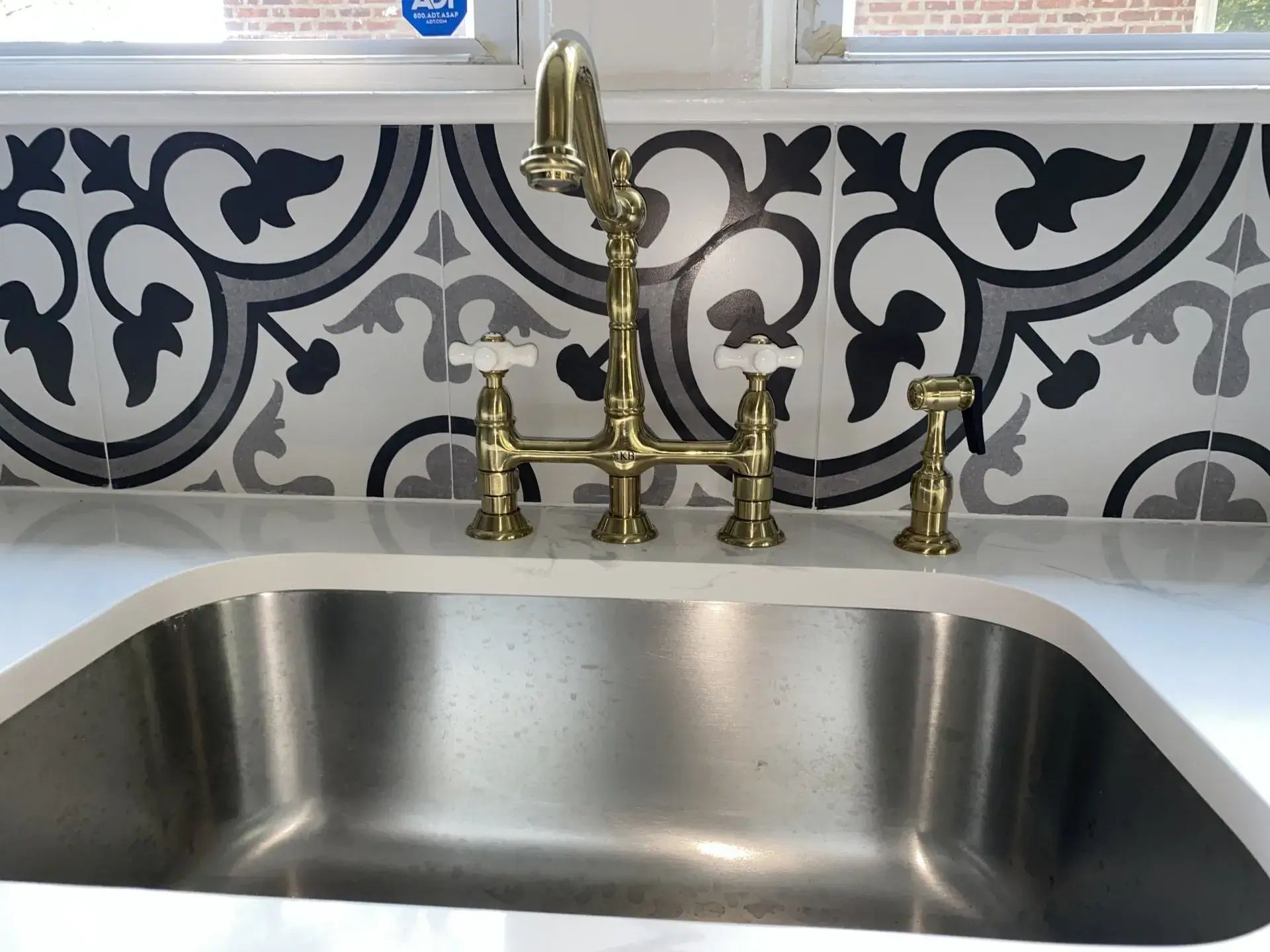 Brass bridge kitchen faucet installed over an undermount stainless sink