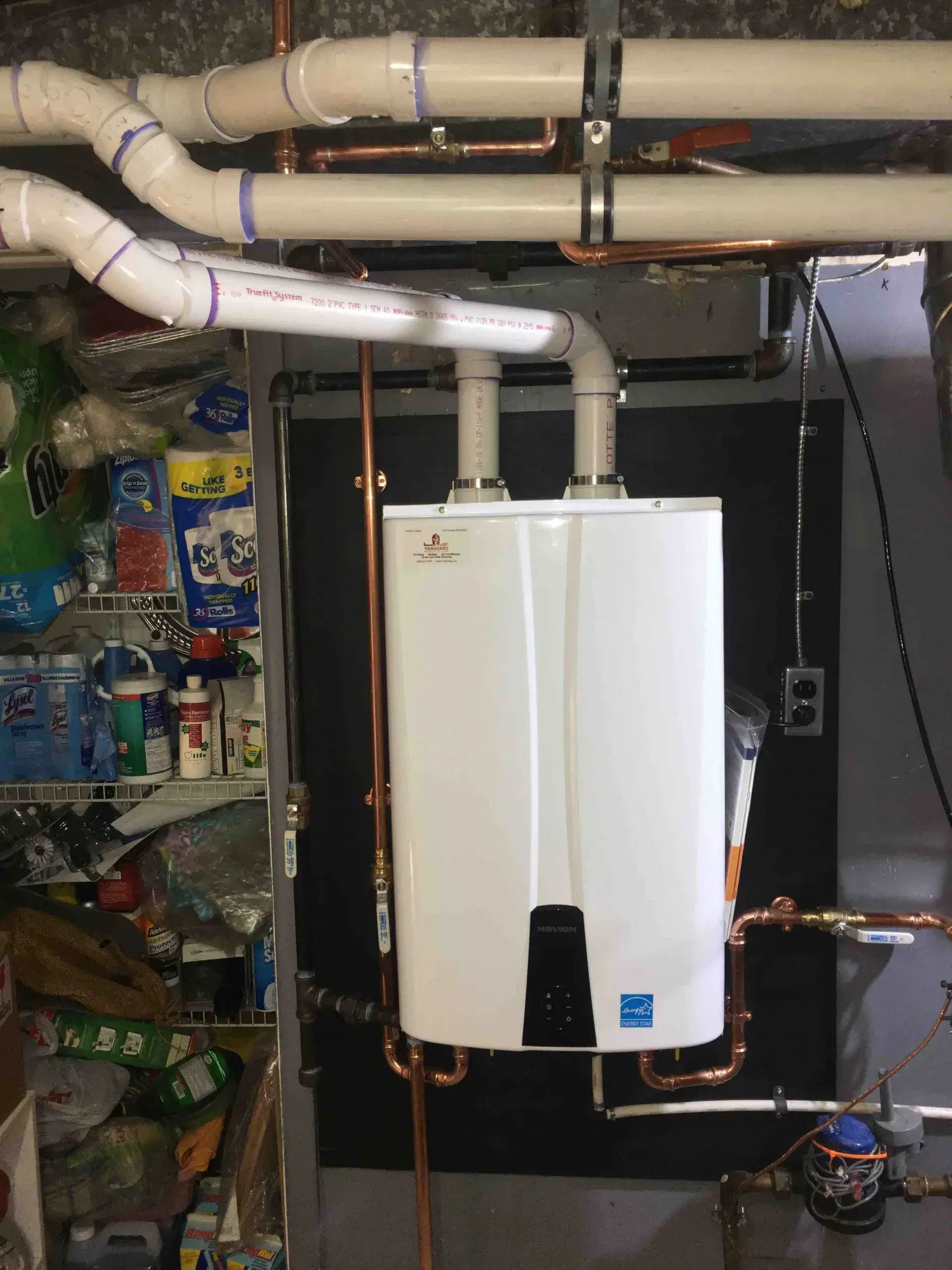 Wall-mounted tankless water heater installed in a utility closet